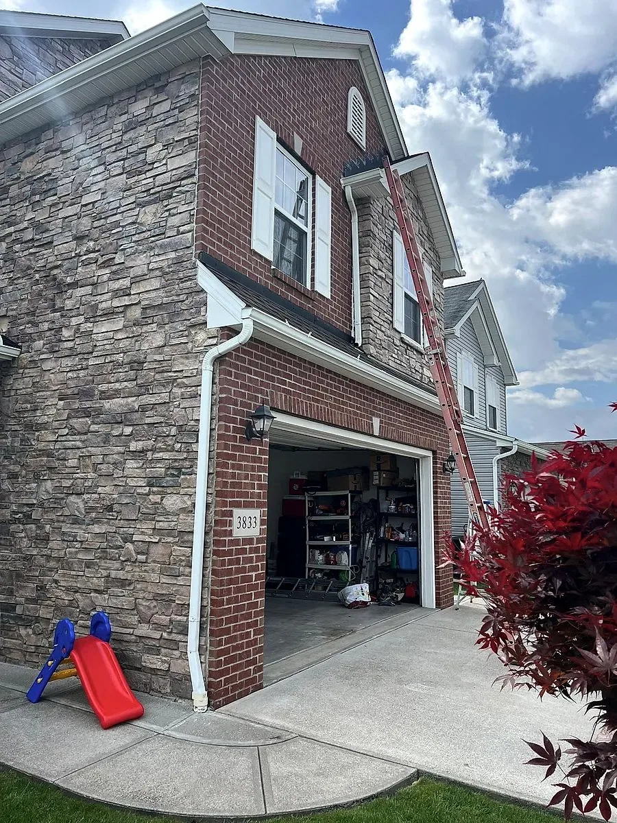 Stone and brick home with a ladder set for roof work in Lorain, Ohio