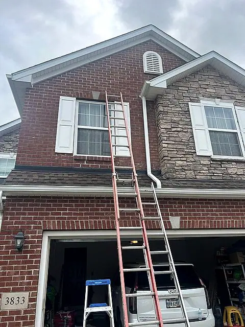Brick facade with ladders staged for roofing in Lorain, Ohio