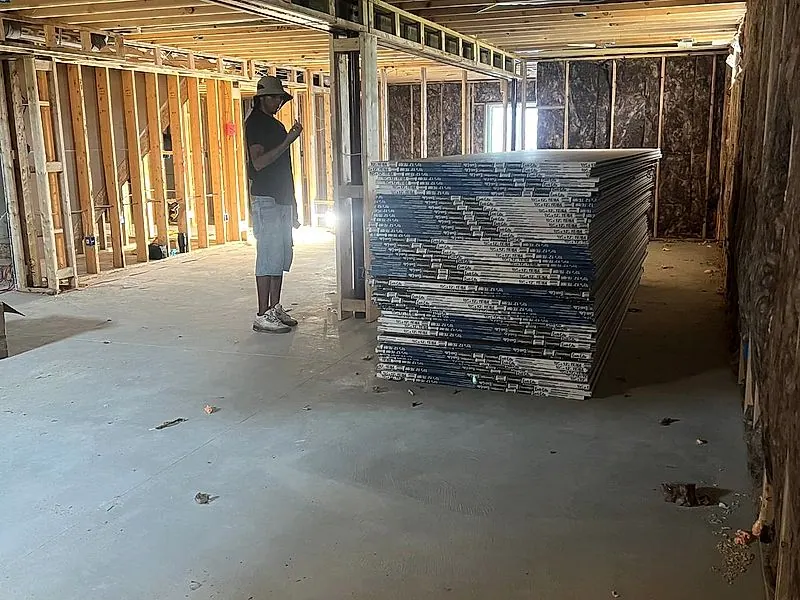 Drywall boards stacked in a basement before hanging and finishing